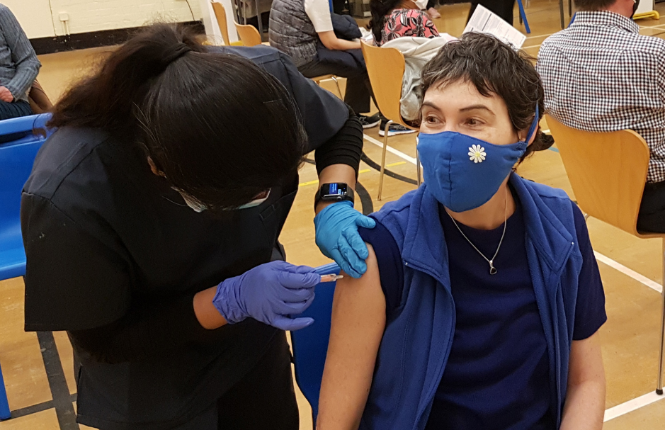 Healthcare worker administering COVID-19 vaccine to woman