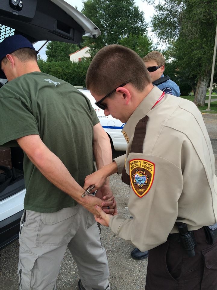 MCSO cadet handcuffing mock suspect behind vehicle. 